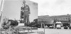  ??  ?? A billboard is displayed as vehicles sit at fuel pumps at a Petroleos de Venezuela gas station in Caracas, Venezuela, on Dec 29, 2015.