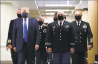  ?? Associated Press ?? President Donald Trump, foreground left, wears a face mask as he walks with others down a hallway during a visit to Walter Reed National Military Medical Center in Bethesda, Md., on July 11.