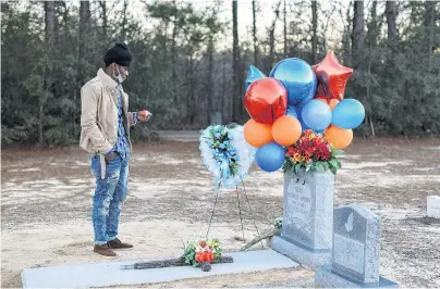  ?? PHOTO: REUTERS ?? Life cut short . . . A man holds a candle next to the grave of Ahmaud Arbery — an unarmed young black man shot and killed after being chased by a white former law enforcemen­t officer and his son — during a vigil to mark the first anniversar­y of his death, at New Springfiel­d Baptist Church in Waynesboro, Georgia, the United States yesterday.