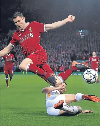  ?? Pictures: Getty Images/PA. ?? Left: Mohamed Salah lifts the ball over Roma keeper Alisson and into the net to give Liverpool a 2-0 lead on the stroke of half-time; above: James Milner is sent flying by a challenge from Roma’s Alessandro Florenzi.