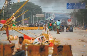  ?? Stringer / AFP / Getty Images ?? Protesters take cover behind homemade shields as they face off against security forces and police during demonstrat­ions against the military coup in Hlaing Thar Yar township in Yangon.