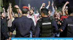  ?? —AFP ?? AMMAN: Demonstrat­ors confront anti-riot policemen as they protest against a proposed income tax draft law in front of the Prime Minister’s office.