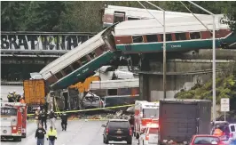  ?? ELAINE THOMPSON/THE ASSOCIATED PRESS ?? Cars from an Amtrak train on Monday lay spilled onto Interstate 5 below, alongside smashed vehicles as some train cars remain on the tracks above, in DuPont, Wash. Seventy-eight passengers and five crew members were aboard when the train, moving at...