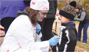  ??  ?? Undead nurse Jenn Pippus attempts to find a heartbeat on the body of Leon (Skeletor) Bi before the start of the Zombie Run. Photo by Jason G. Antonio