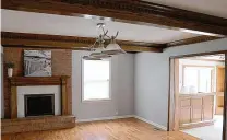  ?? ?? Dentil wood beams accent the ceiling of the family room and complement the wood mantel and woodwork surroundin­g the brick fireplace. The fireplace is tucked off to one side and has a raised brick hearth and is flanked by one large side-facing window.