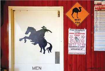  ??  ?? Posters adorn the wall next to the door for the men’s toilet at the Stonehenge Pub.