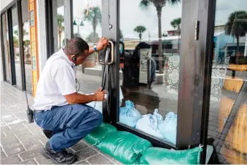  ?? — AFP photos ?? Patrick Adams seals the main door of a restaurant with gaffer tape as Hurricane Ian approaches in Clearwater, Florida.