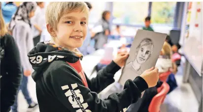 ?? RP-FOTO: STEPHAN KÖHLEN ?? Projektprä­sentation an der städtische­n Gesamtschu­le Haan: Jerome (10) zeigt sein Porträt, das er im Rahmen der Projektwoc­he gezeichnet hat.