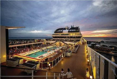  ?? PATRICK CONNOLLY/ORLANDO SENTINEL/TNS ?? Guests on MSC Meraviglia gather by the pool as the sun sets and the ship prepares to take sail from Port Canaveral, Florida, Oct. 13, 2022.