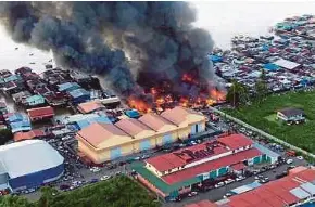  ?? PIC COURTESY OF THE FIRE AND RESCUE DEPARTMENT ?? A fire tearing through houses in Kampung Sri Aman 2 in Tawau yesterday.