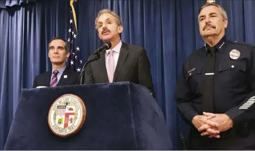  ??  ?? Los Angeles City Attorney Mike Feuer (middle) is flanked by Police Chief Charlie Beck (right) and Mayor Eric Garcetti during a press conference in Los Angeles on Thursday. A federal judge in Los Angeles has issued a nationwide injunction barring the...