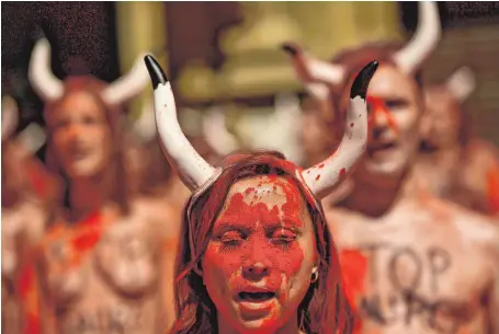  ?? FOTO: DPA ?? Menschen mit aufgesetzt­en Stierhörne­rn demonstrie­ren in Pamplona gegen das Stierkampf­festival San Fermin.