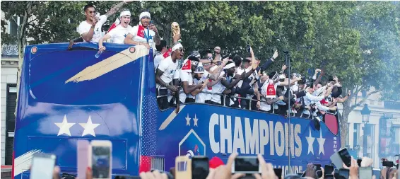  ?? AP ?? Crowds cheer the French team parading aboard a bus on the famed Champs-Elysées in Paris on Monday after their 4-2 victory over Croatia a day earlier in the World Cup final.