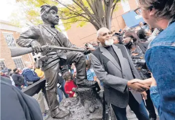  ?? MARK HUMPHREY/AP ?? Sculptor Joe Howard shakes hands Saturday with people in Franklin, Tennessee, at the unveiling of his work, a statue honoring the contributi­ons of Black enslaved men who enlisted in the Union Army in the Civil War. The massive bronze statue will take its place in front of the Historic Franklin Courthouse across the street from a Confederat­e statue.