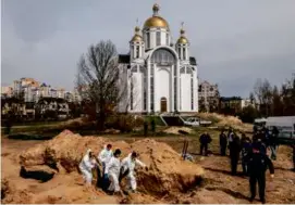  ?? DANIEL BEREHULAK/NEW YORK TIMES ?? Left: In April, workers exhumed the bodies of at least 119 civilians, killed during the Russian occupation, from a mass grave near Bucha’s All Saints Church.