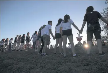  ?? AFP ?? People hold hands around a memorial in front of Marjory Stoneman Douglas High School where 17 people were killed last Wednesday.