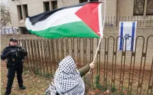  ?? ?? متظاهر يرفع العلم الفلسطينى أمام السفارة الإسرائيلي­ة بأمريكا