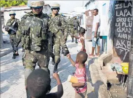  ??  ?? BRAZILIAN peacekeepe­rs greet children. In recent years, the overall U.N. force in Haiti has been plagued by controvers­y, including a cholera outbreak.