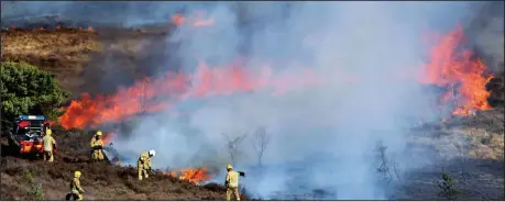  ??  ?? Ring of flames: Fire crews struggle to bring the inferno under control as it tears through the dry undergrowt­h