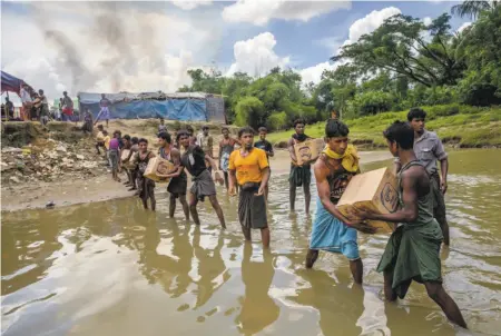  ?? Dar Yasin / Associated Press 2017 ?? Rohingya Muslims carry food in September from Bangladesh to a no-man’s-land at the border with Myanmar.