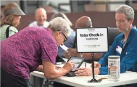  ?? LIZ DUFOUR/THE CINCINNATI ENQUIRER VIA AP, FILE ?? A poll worker prepares to give a ballot to a voter in Blue Ash, Ohio.