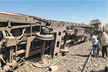  ?? AFP via Getty Images ?? People in Egypt’s southern Sohag province examine the wreckage after two trains collided. Egypt’s national rail system has a history of deadly accidents, badly maintained equipment and mismanagem­ent.