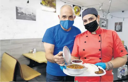  ?? RICARDO RAMIREZ BUXEDA/ORLANDO SENTINEL PHOTOS ?? Ramon Martinez and his wife, chef Barbara Martinez, show off a plate of ropa vieja at Abuelita’s Kitchen in the College Park Cafe.