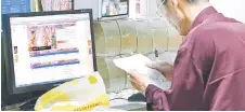  ?? — AFP photo ?? A man looks at his note on informatio­n of the 2018 Russia World Cup tournament­s at a China Sports Lottery outlet in Shanghai.