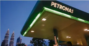  ?? — EPA ?? Dark days: The Petronas Twin Towers rising behind a Petronas petrol station in Kuala Lumpur.