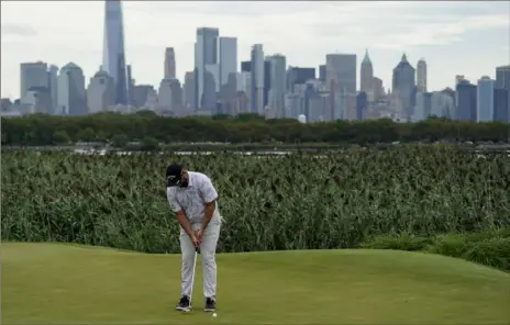  ?? Associated Press ?? Jon Rahm sinks his putt on the 14th green as the Manhattan skyline looms in the distance in the second round at the Northern Trust Friday at Liberty National Golf Course in Jersey City, N.J.