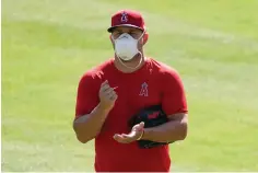  ?? AP Photo/Ashley Landis ?? ■ Los Angeles Angels center fielder Mike Trout (27) stands on the field wearing a face mask Friday during a baseball practice at Angels Stadium in Anaheim, Calif.