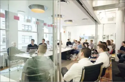  ?? VINCENT TULLO, NEW YORK TIMES ?? Cameron Winklevoss and his twin brother Tyler, second and third from left at the table, meet with staff in the offices of Gemini, in New York.