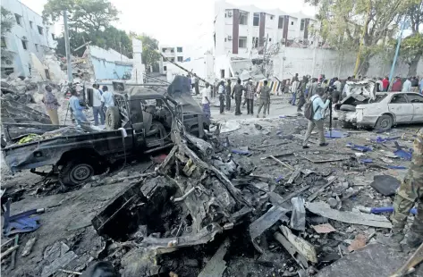  ?? FARAH ABDI WARSAMEH/THE ASSOCIATED PRESS ?? Rescue workers stand near the wreckage of vehicles in Mogadishu, Somalia, on Sunday, after a car bomb was detonated Saturday night. A Somali police officer said security forces ended a night-long siege at a Mogadishu hotel by attackers who stormed the...