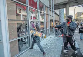  ?? /AFP ?? Shattered: A demonstrat­or vandalises a restaurant in Los Angeles on May 30 during a protest against the death of George Floyd at the hands of police in Minneapoli­s.