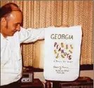  ?? CONTRIBUTE­D BY LIGAYA FIGUERAS ?? In this Christmas photo taken in the late 1970s, he holds the packaging from a gift of Georgia peanuts, one of his favorite snack foods.