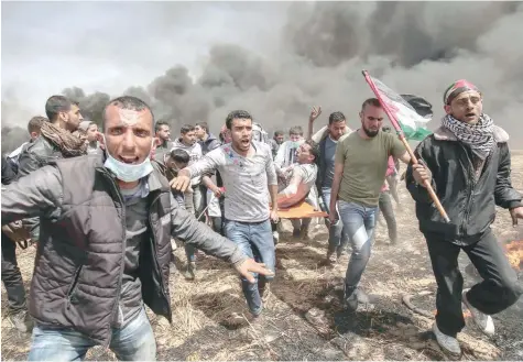  ?? — AFP ?? An injured Palestinia­n protester is carried by fellow demonstrat­ors during clashes with Israeli security forces near the border with Israel, east of Khan Yunis, in the southern Gaza Strip, on Friday.