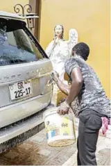  ??  ?? En ung mann vasker en av de dyre bilene til «Angel» Obinim. Han har et titall store, eksklusive biler, samt flere villaer og store eiendommer.