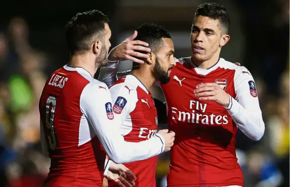  ?? — Reuters ?? Reaching a milestone: Theo Walcott (centre) is congratula­ted by Lucas Perez (left) and Gabriel Paulista after scoring Arsenal’s second goal against
Sutton United in the English FA Cup fifth round on Monday.