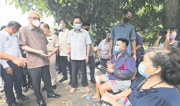  ?? ?? Photo shows Prime Minister Datuk Seri Ismail Sabri Yaakob (second left) talking to victims of a landslide at Kampung Madsiang in Penampang, Sabah, in September. — Bernama photo