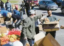  ?? JONATHON GRUENKE/STAFF FILE ?? Virginia Peninsula Foodbank volunteers prepare boxes of food to be distribute­d to vehicles during a drive-thru mobile food pantry at Darling Stadium in Hampton in April 2020.