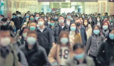  ?? BLOOMBERG ?? ■
Commuters wearing protective masks walk through Hong Kong Station on Wednesday.