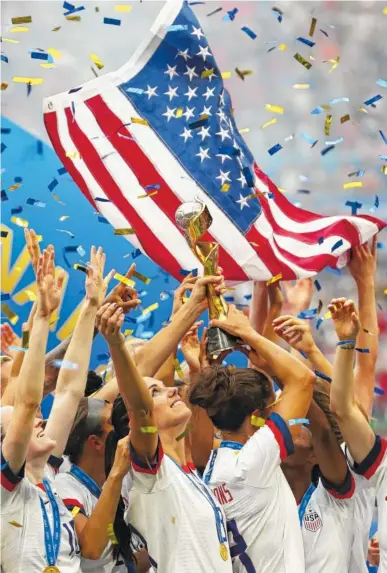  ?? AP PHOTO/FRANCISCO SECO ?? Alex Morgan, center, looks up as her U.S. teammates hold the trophy after winning the Women’s World Cup on Sunday in Lyon, France. The United States beat the Netherland­s 2-0 to win the tournament for the fourth time.