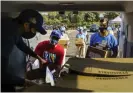  ?? Photograph: Damian Dovarganes/AP ?? Luis Alarcon, Bresee youth center volunteer, gets help loading the foundation’s van with Thanksgivi­ng supplies at Dodger Stadium in Los Angeles on 19 November.