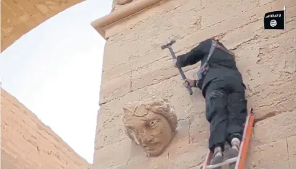  ?? MILITANT VIDEO VIA AP ?? A militant destroys a face on a wall in Hatra, a recognised Unesco World Heritage site 110km southwest of Mosul in Iraq. The Islamic State’s attacks on these treasures are a likely cover-up for its lucrative business in selling looted artefacts.