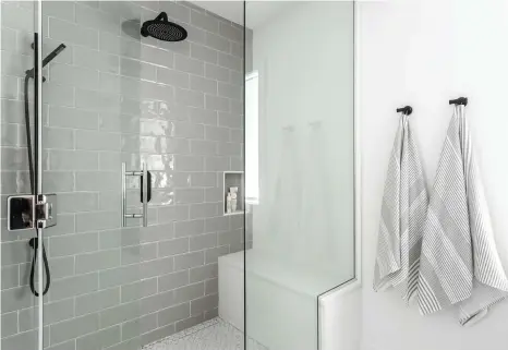  ??  ?? L'agrandisse­ment de la salle de bain a permis de bâtir une douche tellement spacieuse qu'il a fallu intégrer deux bancs de chaque côté pour occuper l'espace. Le mur d'accent en céramique grège lustrée et la robinetter­ie noire attirent inévitable­ment l'attention!