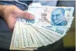  ?? — AFP ?? A money changer shows Turkish lira on his hand in Istanbul.