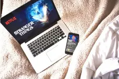  ?? — Gabby Jones/Bloomberg ?? A laptop and iPhone display the home screen for the Netflix original series ‘Stranger Things’ in an arranged photograph taken in New York on Apr 12.