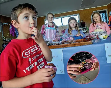  ?? PHOTO: WARWICK SMITH/FAIRFAX NZ ?? Louis Macquet, left, enjoys a cupcake bought from Eden Brown, 9, Sophia Brown and Maddison Kerr, both 7.