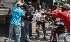  ?? (AP/Joseph Odelyn) ?? Rice is distribute­d to residents Monday in Les Cayes, Haiti, two days after a 7.2-magnitude earthquake struck the southweste­rn part of the hemisphere’s poorest nation. Video at arkansason­line.com/817haiti/.