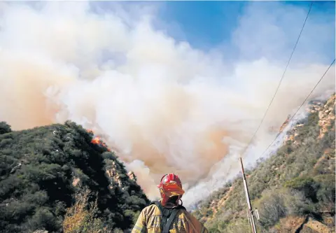  ?? REUTERS ?? Firefighte­rs battle the Woolsey Fire on Sunday as it continues to burn in Malibu, California.